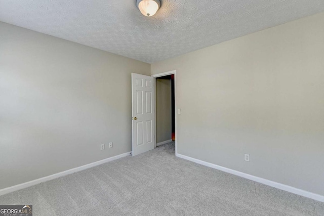 empty room with a textured ceiling and light carpet