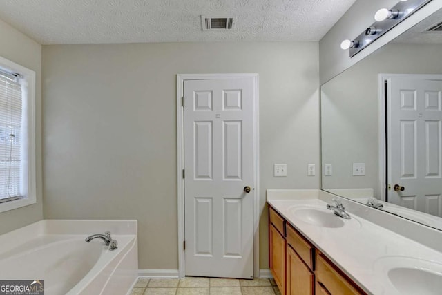 bathroom featuring tile patterned flooring, vanity, a textured ceiling, and a tub