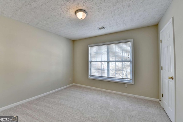 empty room with a textured ceiling and light colored carpet