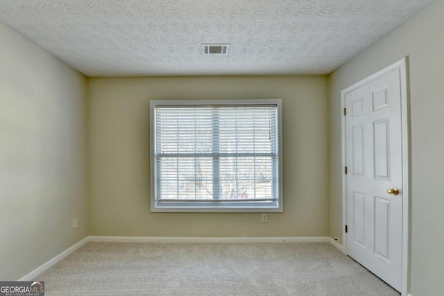 unfurnished room featuring a textured ceiling and light colored carpet