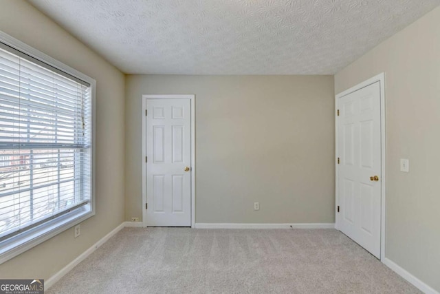 spare room featuring a textured ceiling and light carpet