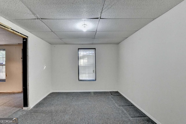 carpeted empty room featuring a drop ceiling