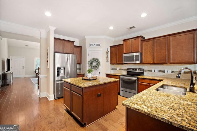 kitchen with a kitchen island, stainless steel appliances, crown molding, and sink