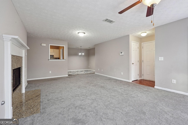 unfurnished living room featuring a textured ceiling, ceiling fan, a premium fireplace, and dark carpet