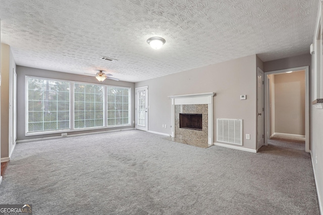 unfurnished living room with ceiling fan, a high end fireplace, a textured ceiling, and carpet