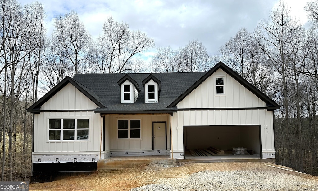 modern inspired farmhouse with board and batten siding, roof with shingles, driveway, and a garage