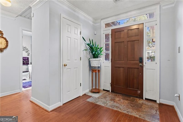 entryway with a textured ceiling, ornamental molding, and hardwood / wood-style flooring