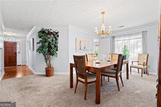 carpeted dining area featuring a notable chandelier, a textured ceiling, and ornamental molding