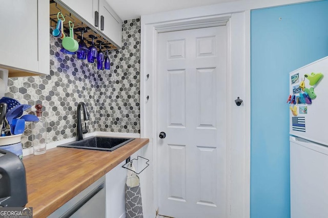 kitchen with white cabinets, refrigerator, decorative backsplash, and sink