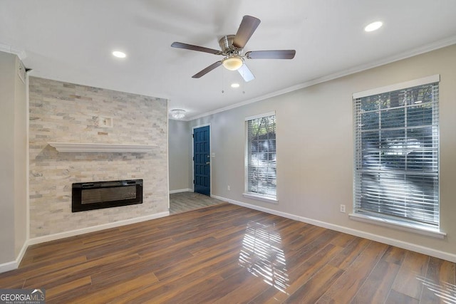 unfurnished living room with ceiling fan, crown molding, a large fireplace, and dark wood-type flooring