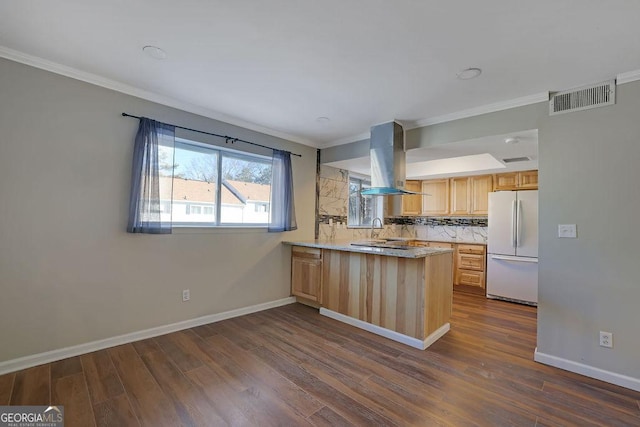 kitchen featuring island range hood, kitchen peninsula, white refrigerator, decorative backsplash, and light brown cabinets