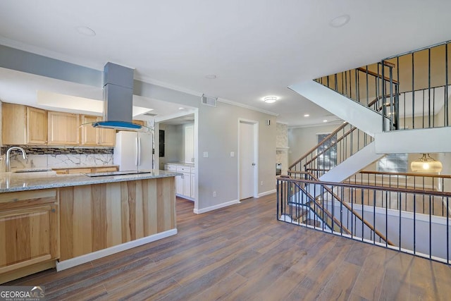 kitchen featuring white fridge, island range hood, light stone countertops, ornamental molding, and light brown cabinetry