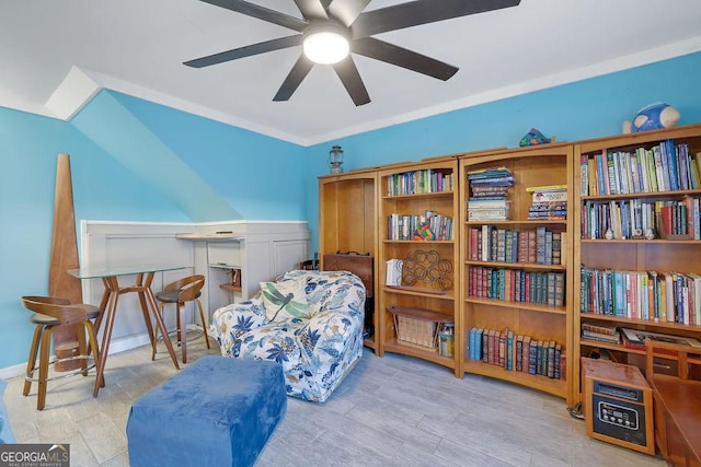 living area with ceiling fan, crown molding, and light hardwood / wood-style flooring