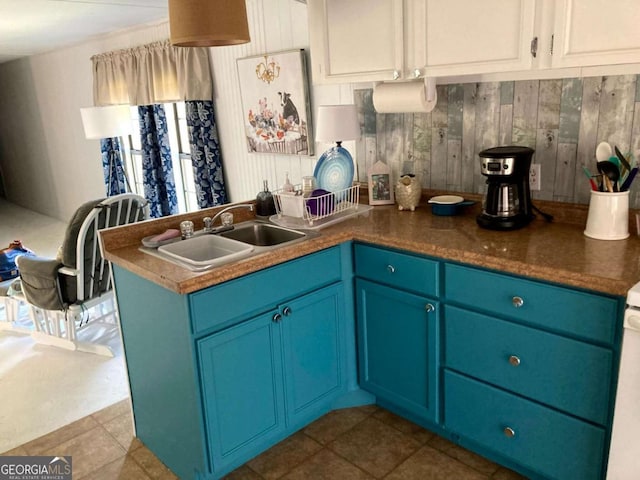 kitchen featuring sink, wooden walls, white cabinetry, tile patterned floors, and blue cabinetry