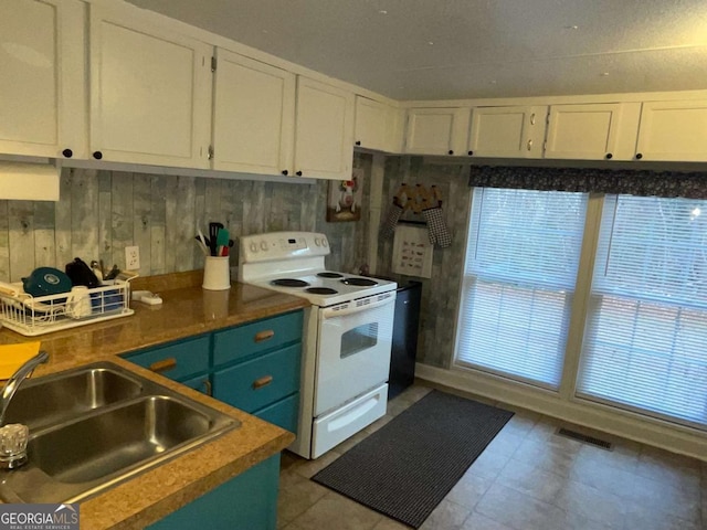 kitchen with sink, white cabinets, wood walls, and electric range