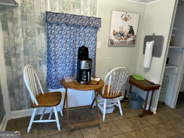 tiled dining room featuring wood walls