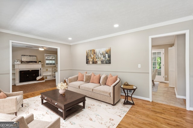 living room with ceiling fan, light wood-type flooring, and crown molding