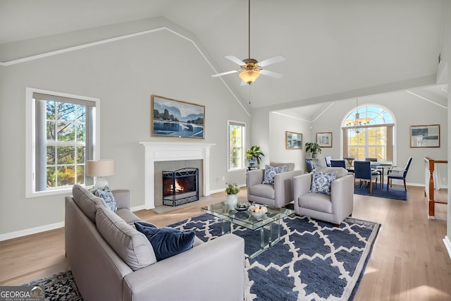 living room featuring lofted ceiling, light wood-type flooring, a tiled fireplace, and ceiling fan