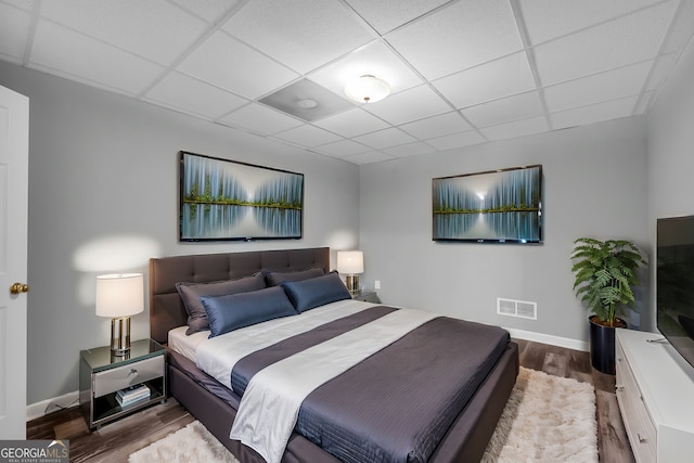 bedroom with wood-type flooring and a drop ceiling