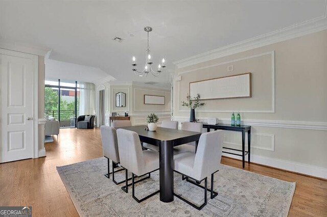 dining room featuring a chandelier, ornamental molding, and light wood-type flooring