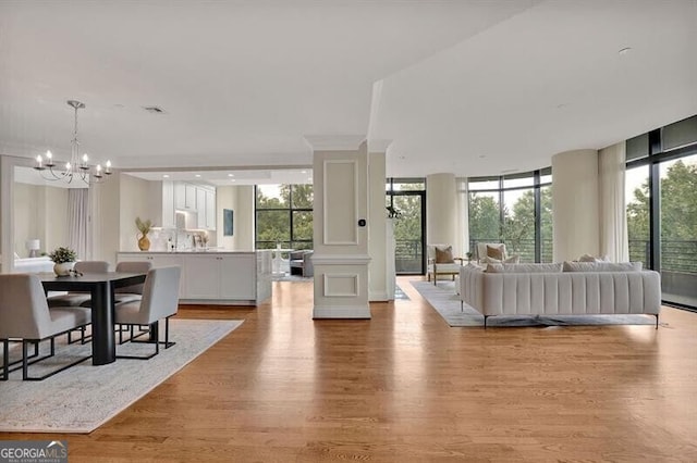 living room featuring floor to ceiling windows, an inviting chandelier, and light hardwood / wood-style floors