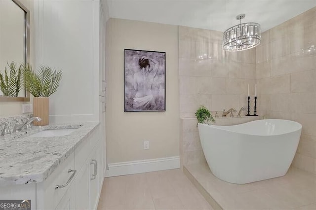 bathroom with a tub, vanity, tile patterned floors, tile walls, and an inviting chandelier