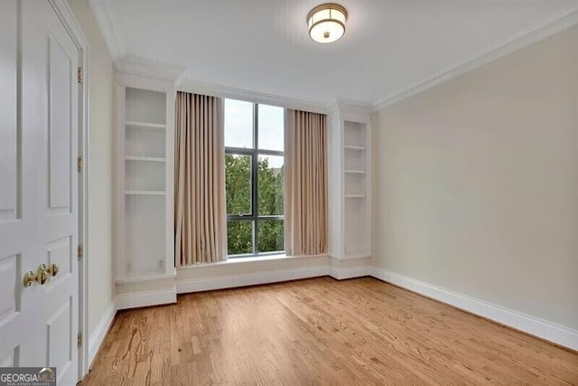 spare room with ornamental molding and light wood-type flooring