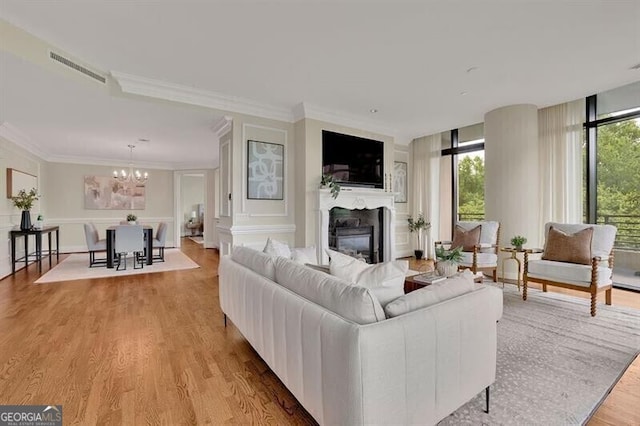 living room featuring ornamental molding, a notable chandelier, light hardwood / wood-style flooring, and expansive windows