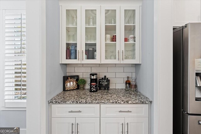 kitchen featuring light hardwood / wood-style floors, appliances with stainless steel finishes, light stone countertops, white cabinetry, and tasteful backsplash