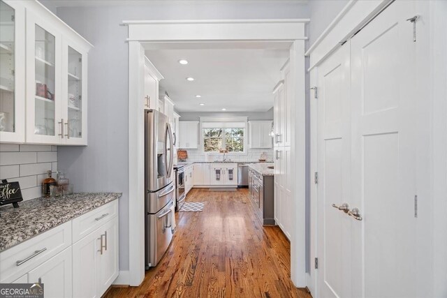 kitchen with sink, stainless steel dishwasher, backsplash, and white cabinetry