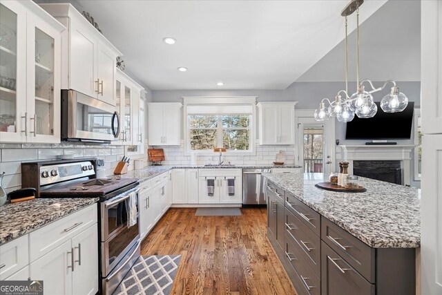 kitchen with light stone countertops, appliances with stainless steel finishes, white cabinetry, and sink