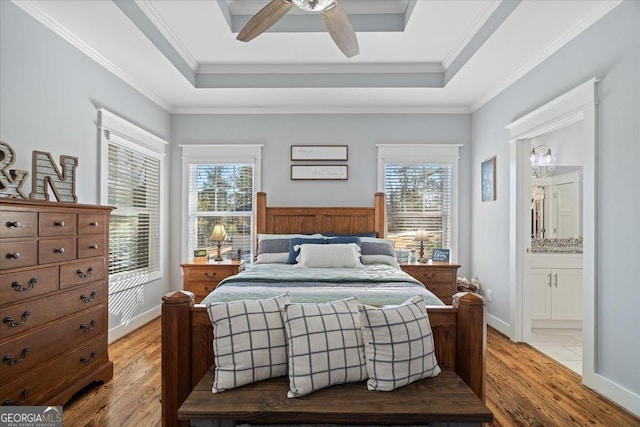 bedroom featuring ensuite bathroom, ceiling fan, a tray ceiling, and light hardwood / wood-style floors