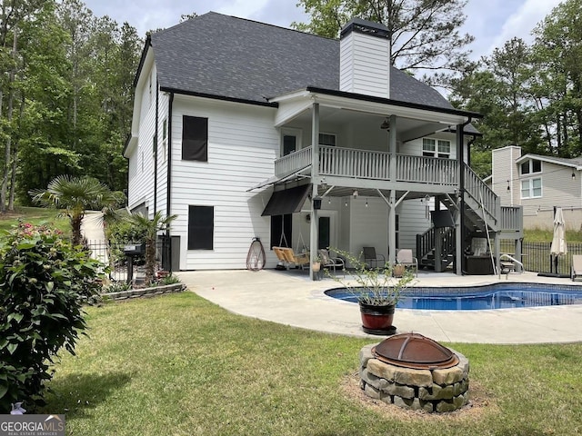 back of property with a balcony, a fire pit, a yard, and a patio area