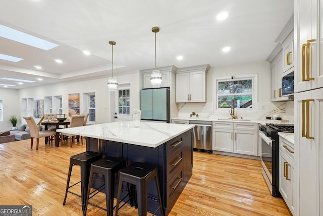 kitchen featuring gas stove, dishwasher, hanging light fixtures, refrigerator, and a center island