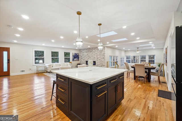 kitchen featuring decorative light fixtures, a kitchen bar, a center island, and light hardwood / wood-style flooring