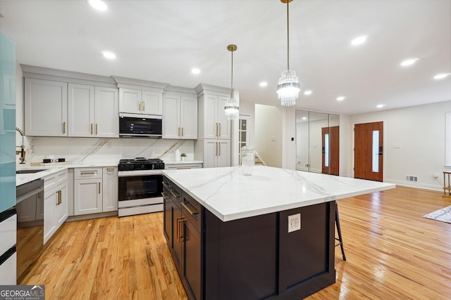 kitchen featuring pendant lighting, dishwasher, a center island, gas stove, and tasteful backsplash