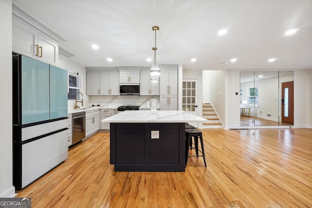 kitchen featuring pendant lighting, a center island, dishwasher, light hardwood / wood-style floors, and refrigerator