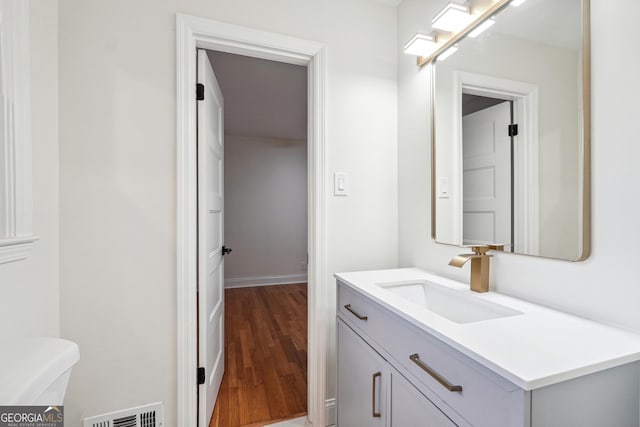 bathroom featuring toilet, vanity, and wood-type flooring