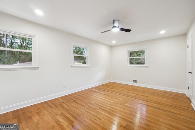 empty room featuring ceiling fan, a healthy amount of sunlight, and light hardwood / wood-style flooring