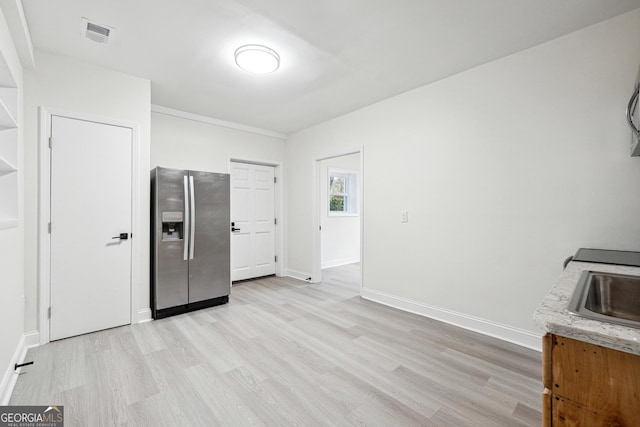 interior space with stainless steel refrigerator with ice dispenser, light hardwood / wood-style floors, and sink