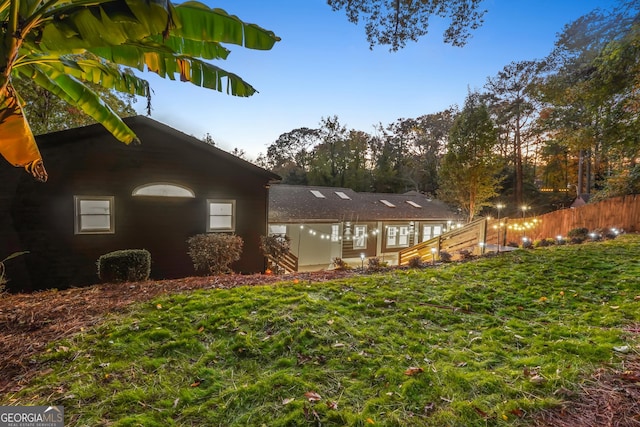 property exterior at dusk featuring a lawn