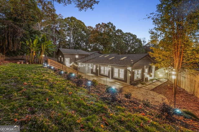 back house at dusk with a patio area and a yard