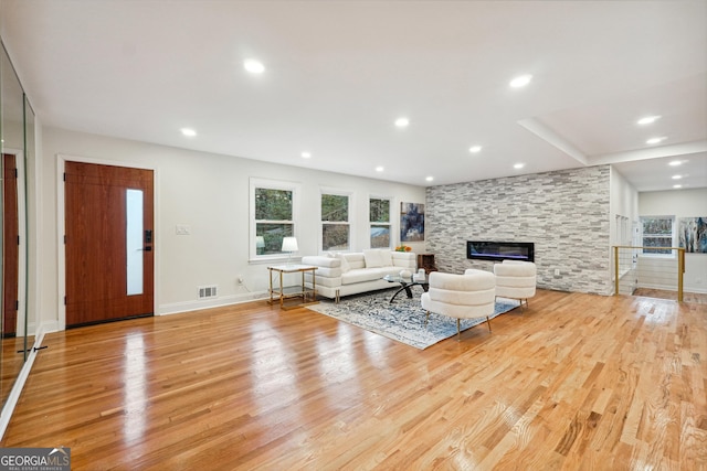 unfurnished living room with light hardwood / wood-style flooring and a stone fireplace