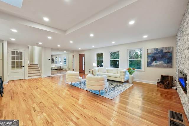 living room featuring light wood-type flooring and a stone fireplace