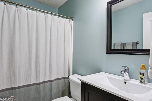 bathroom with toilet, vanity, and a textured ceiling