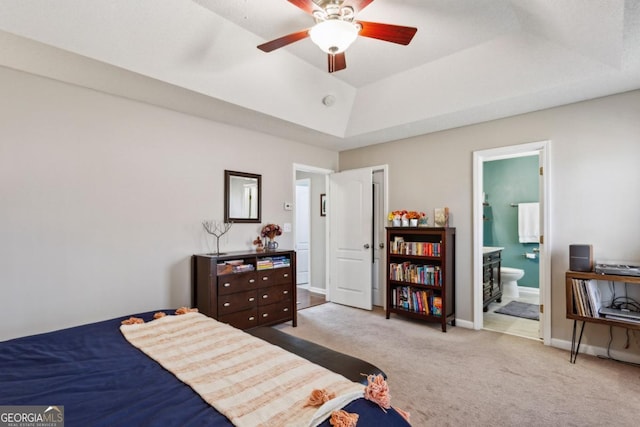 bedroom with ensuite bath, light colored carpet, ceiling fan, and a tray ceiling