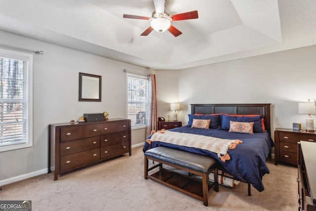 carpeted bedroom with ceiling fan and a tray ceiling