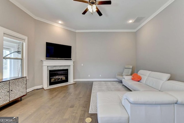 living room featuring ceiling fan, crown molding, a fireplace, and wood-type flooring