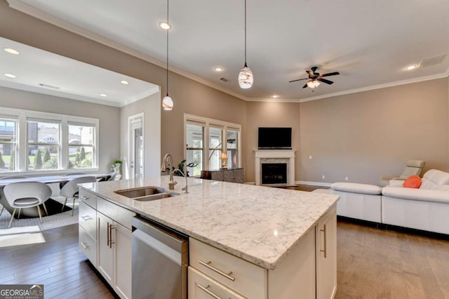 kitchen with light stone countertops, dishwasher, decorative light fixtures, a center island with sink, and sink