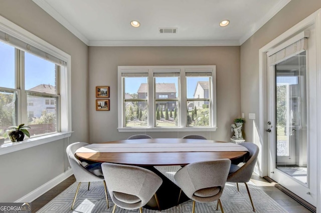 dining space featuring hardwood / wood-style floors, ornamental molding, and a wealth of natural light